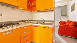 A kitchen with orange cabinets, a gas stove, and a sink. - 2668 Casa Conchiglia (Gallipoli)