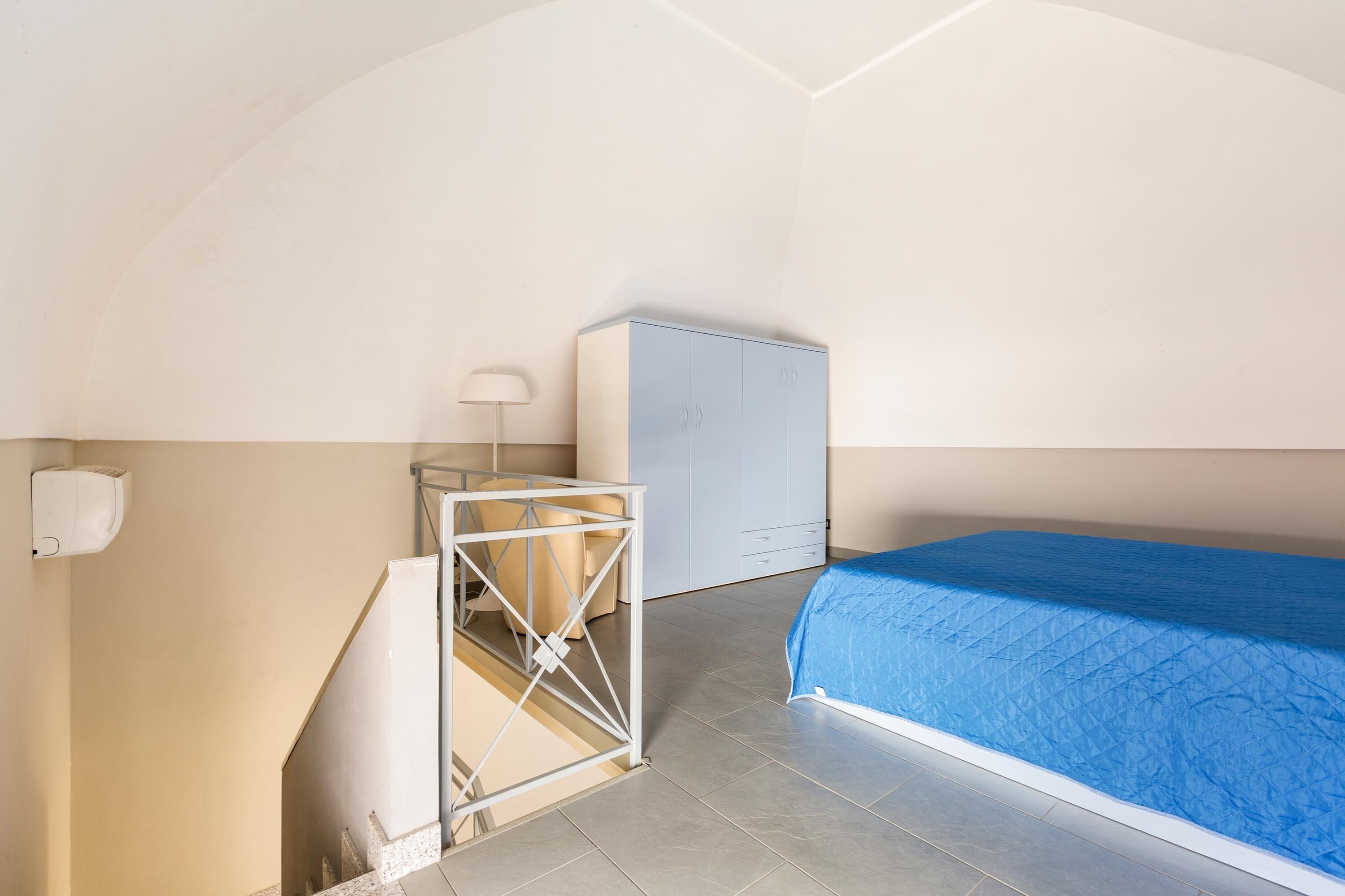 A bedroom with a bed, a wardrobe, a desk, and a chair.