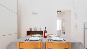 A dining area with a table set for two, chairs, and a bottle of red wine. - 2380 Casa Crispi (Alezio)