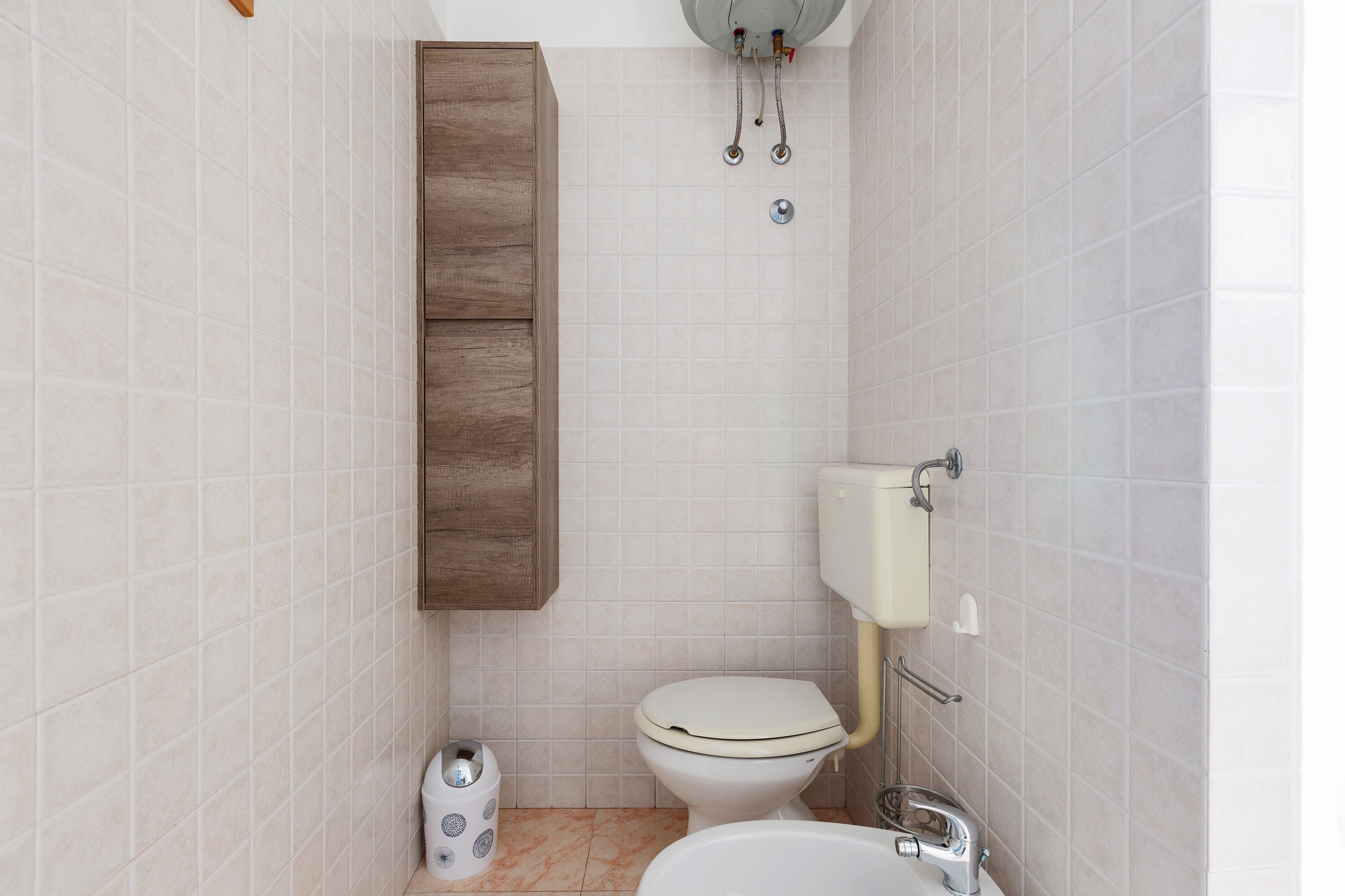 A bathroom with a toilet, sink, and cabinet.