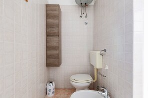 A bathroom with a toilet, sink, and cabinet. - 2380 Casa Crispi (Alezio)