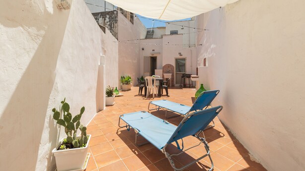 A sunlit patio with two blue lounge chairs, a small table, and a potted cactus. - 2380 Casa Crispi (Alezio)