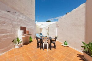 A small patio with a table and chairs, surrounded by white walls and potted plants. - 2380 Casa Crispi (Alezio)