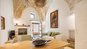 A cozy room with a wooden table, a fireplace, a green chair, and a painting on the wall. - 3011 Casa del Capitano by Barbarhouse (Racale)
