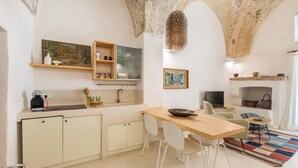 A compact kitchen with a dining area, wooden cabinets, a coffee machine, and a television. - 3011 Casa del Capitano by Barbarhouse (Racale)