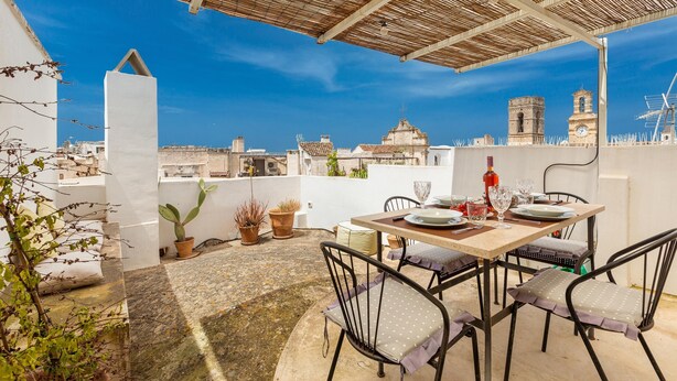 A rooftop terrace with a table set for dining, potted plants, and a view of historic buildings. - 3011 Casa del Capitano by Barbarhouse (Racale)