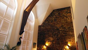 A room with a stone wall, a wooden beam, and a clock.