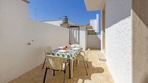 A small outdoor patio with a table set for two, surrounded by white walls and a clear blue sky. - 2967 Dimora di Lucia by Barbarhouse (Taviano)