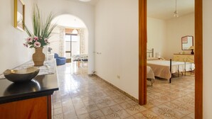 A hotel room with a bed, a bedside table, and a large mirror. There is a hallway leading to a dining area with a table and chairs. - 2967 Dimora di Lucia by Barbarhouse (Taviano)