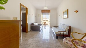 A spacious living area with a sofa, a chair, and a wooden table. A wooden door leads to another room. - 2967 Dimora di Lucia by Barbarhouse (Taviano)