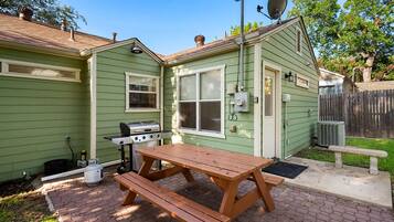 Een groene woning met terras, barbecue en picknicktafel.