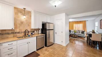 A modern kitchen with white cabinets, a stainless steel refrigerator, and a tiled backsplash.
