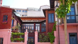 Un bâtiment traditionnel avec un toit en tuiles, une entrée fermée par un portail et une porte bleue.