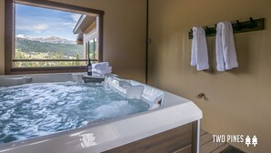 A bathroom with a hot tub, towels on a rack, and a window with a mountain view. - Luxury Ski In/Out ᨒ Beaverhead Condo | Hot Tub | 10 Min Walk to Resort (Big Sky)