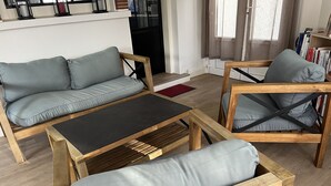Ein modernes Wohnzimmer mit einer Couch, einem Couchtisch und zwei Holzstühlen mit Kissen.