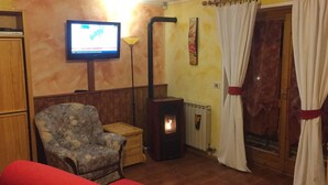 A cozy room with a fireplace, a television, and a patterned armchair. - Holidays on the lake (Valtournenche)