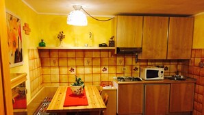 A compact kitchen with wooden cabinets, a microwave, and a stove. - Holidays on the lake (Valtournenche)
