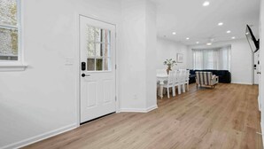 Un vaste espace de vie doté d’un plancher en bois, d’une table à manger avec des chaises, d’un canapé et d’un téléviseur fixé au mur.