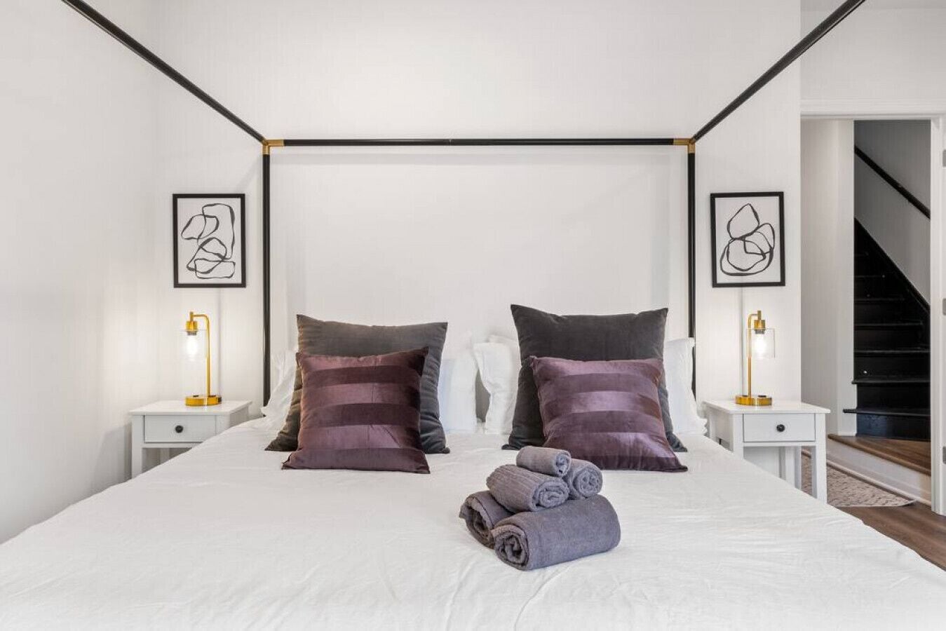 Une chambre à coucher moderne avec un grand lit, deux tables de chevet et un escalier en arrière-plan.