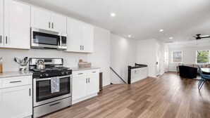 A modern kitchen with white cabinets, stainless steel appliances, and a herringbone wood floor.