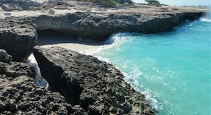 A rocky coastline with clear turquoise water and a narrow passage between large boulders.