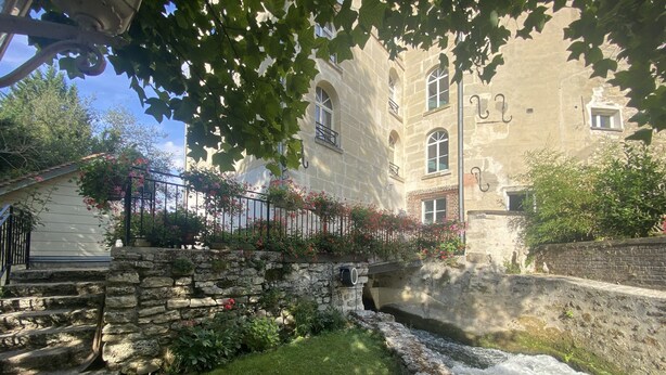 Un escalier en pierre mène à un bâtiment doté d’un petit jardin et d’un élément décoratif aquatique.