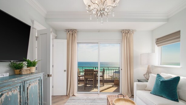 A living room with a television, a sofa, a coffee table, and a view of the ocean through a sliding door. - Sandestin, Gulf Front Condo, Golf Cart (Miramar Beach)
