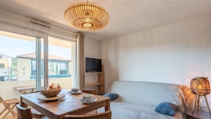 A modern room with a dining table, a sofa, and a TV on a shelf. - Ortal Océan by Interhome (Lacanau)