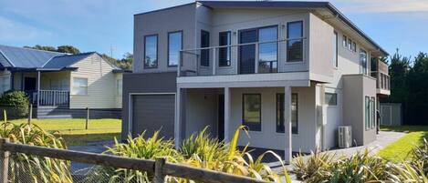 A modern two-story house with a flat roof, large windows, and a covered porch.