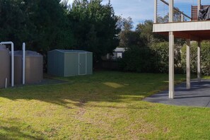 Ein Garten mit einem grünen Schuppen, einer Betonkonstruktion und einem Rasen.