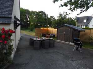 A patio with outdoor furniture, a barbecue grill, and string lights.