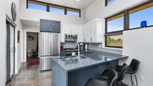 A modern kitchen with a large island, stainless steel appliances, and a view of the outdoors. - Joy of Life @ Palisade Legends (Clifton)