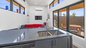 A modern kitchen with a large island, built-in appliances, and a dining area with a view of the backyard. - Joy of Life @ Palisade Legends (Clifton)