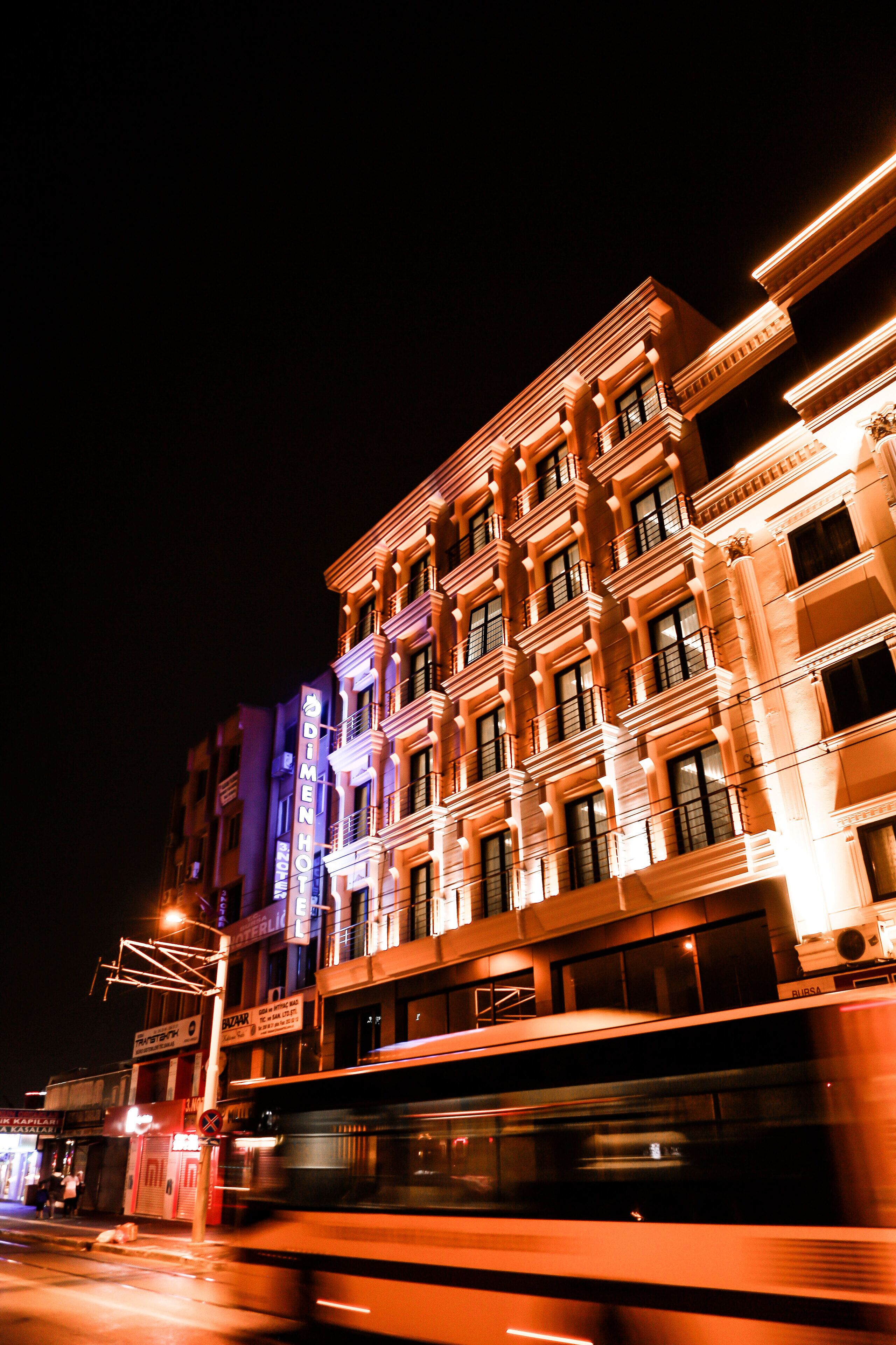 A multi-story building with illuminated signage, including "DIMEN HOTEL" and "RUSSA" on the facade.