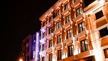 A multi-story building with illuminated signage, including "DIMEN HOTEL" and "RUSSA" on the facade.
