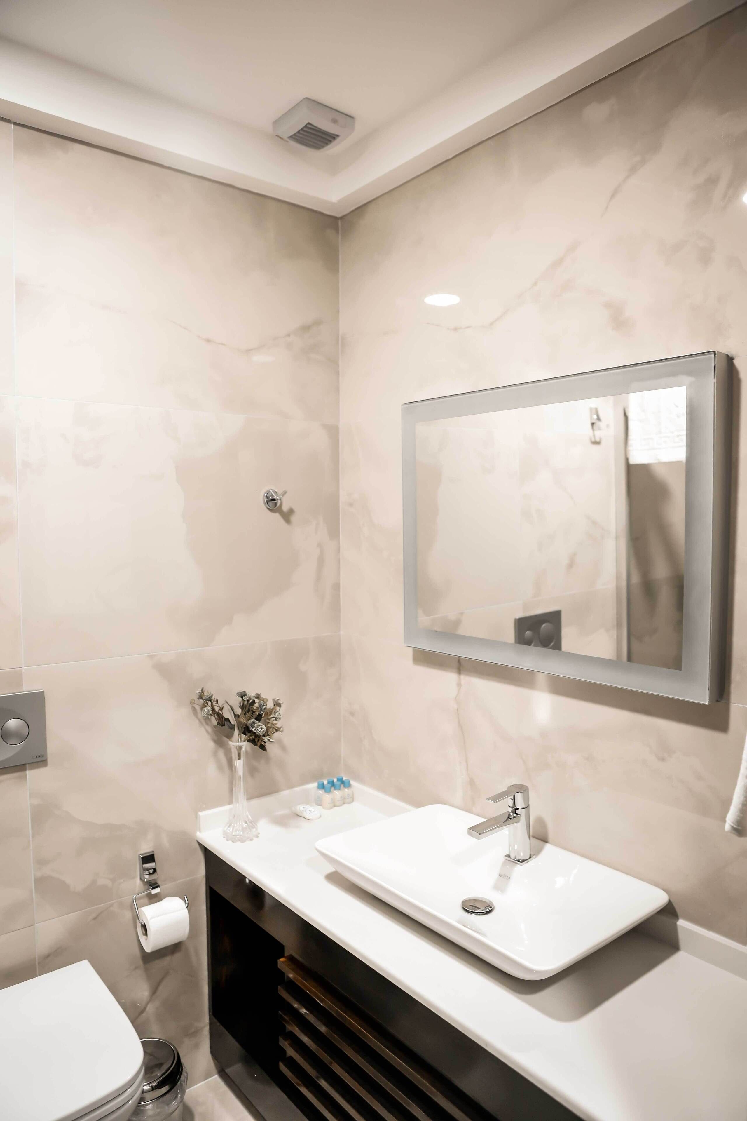 A modern bathroom with a white sink, mirror, and toilet.
