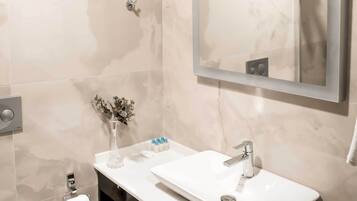 A modern bathroom with a white sink, mirror, and toilet.