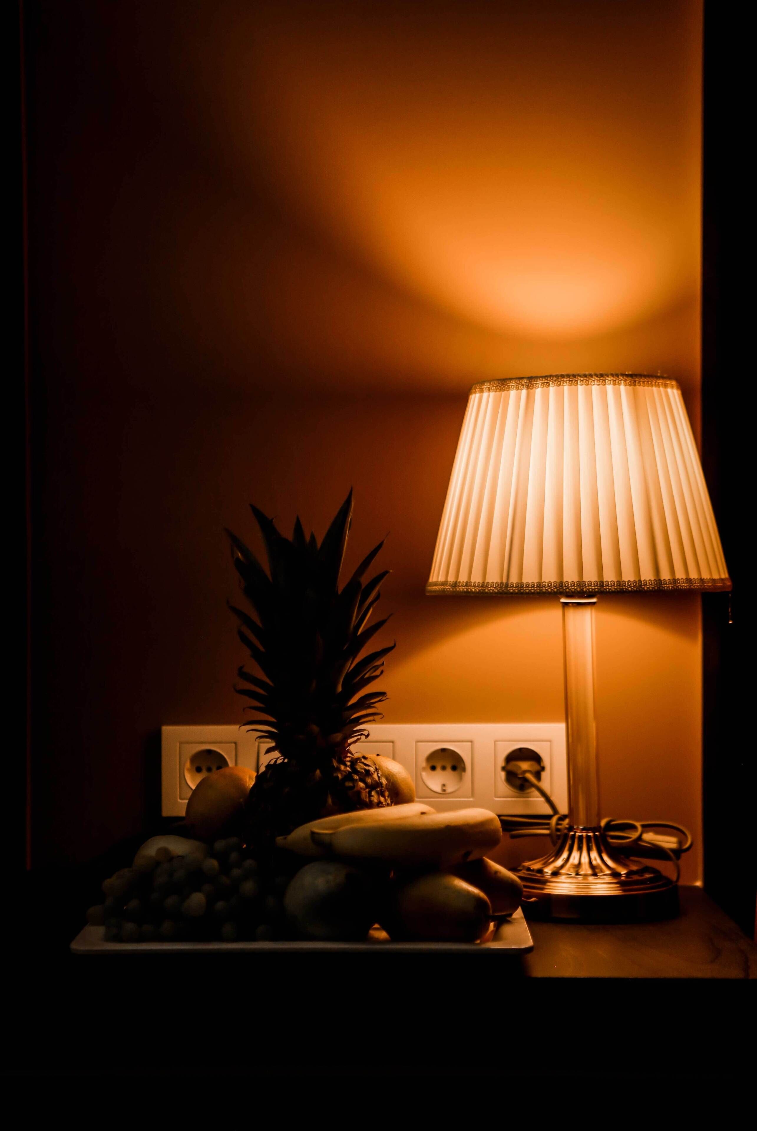 A table with a fruit platter and a lamp.