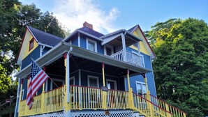 Ein zweistöckiges Haus mit Veranda, Flagge und Treppe.