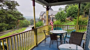 Eine überdachte Veranda mit blauem Boden, gelbener Geländer und Gartenmöbeln, darunter ein Tisch und Stühle.