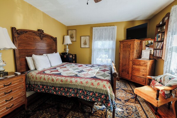 Un dormitorio tradicional con una cama de madera, una mesita de noche, un aparador, una silla y una estantería.