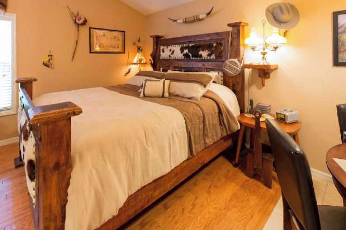 Une chambre confortable avec un lit en bois, une table de chevet avec une lampe et un banc en bois.