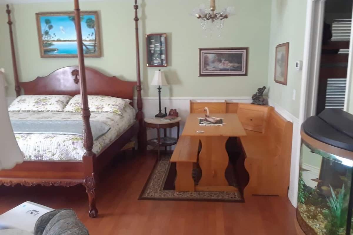Une chambre à coucher avec un lit à baldaquin, une table en bois et un aquarium.