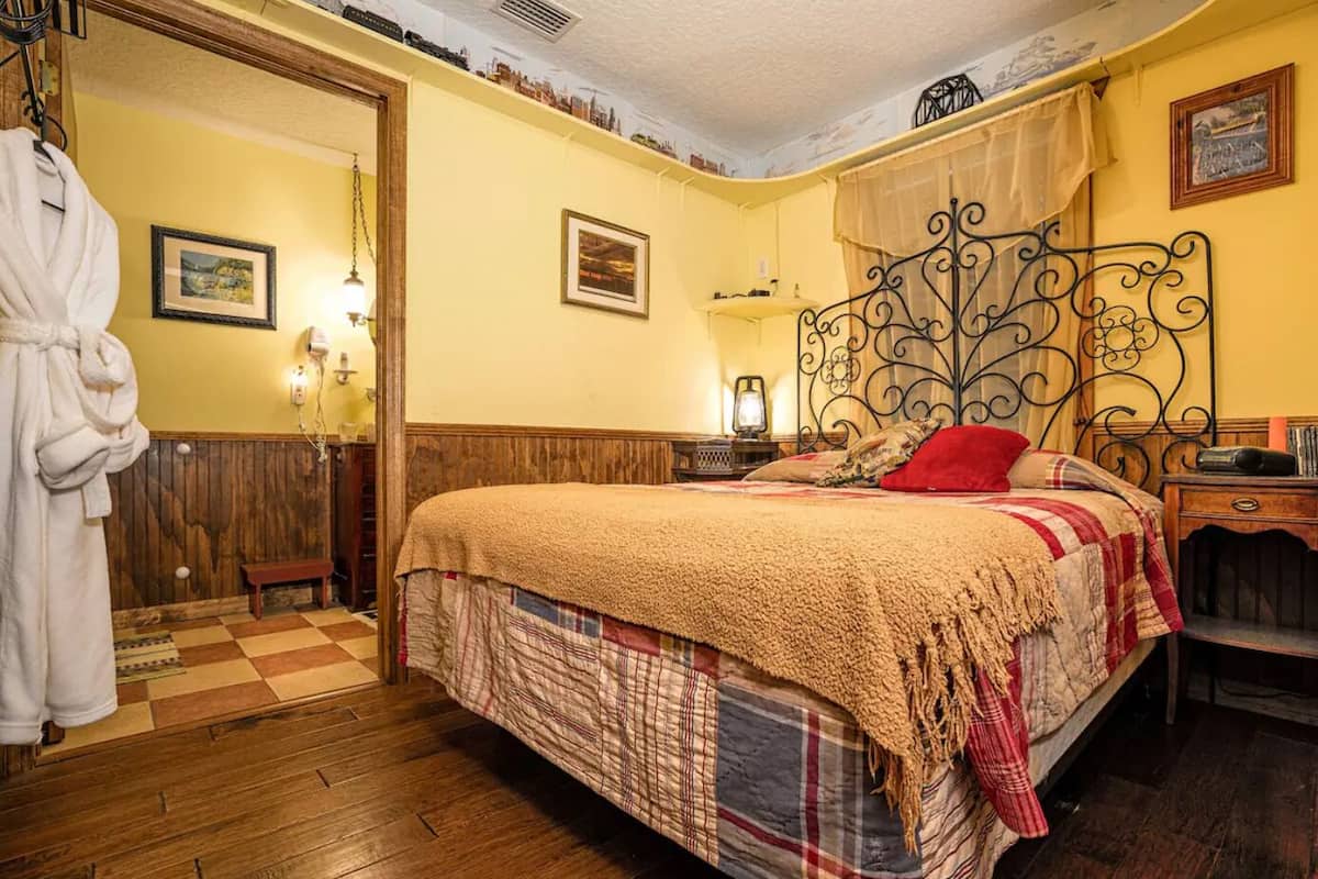 Une chambre confortable avec un grand lit, un plancher en bois, un banc et un peignoir suspendu à un crochet.