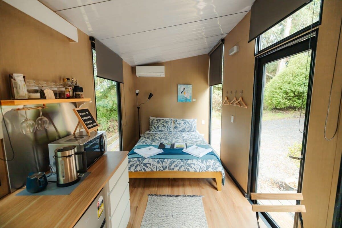 A compact room with a bed, a kitchenette, and a large window.