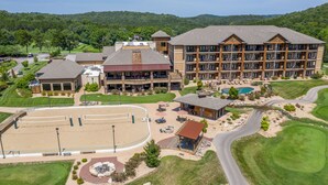 A multi-story hotel with a pool, outdoor seating, and a golf course in the background.