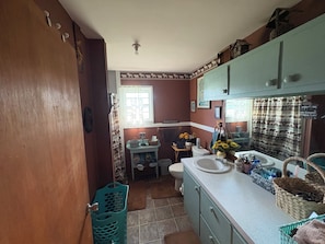 A bathroom with a sink, toilet, and a small window. There are baskets and toiletries on the counter. - Ozarks Home Away from Home (Willow Springs)