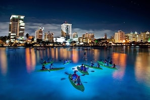 Un paisaje urbano nocturno con una masa de agua tranquila que refleja los edificios.