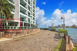 Une propriété située au bord de l’eau, dotée d’une terrasse dallée, d’un mur en pierre et offrant une vue sur la mer.