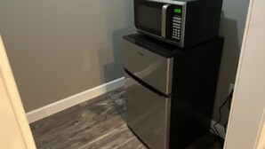 Eine kleine Küchenzeile mit Edelstahlkühlschrank und Mikrowelle.